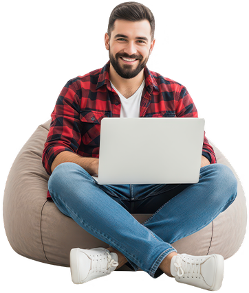 Young man in casual clothes sitting cross-legged on a bean bag working on a laptop